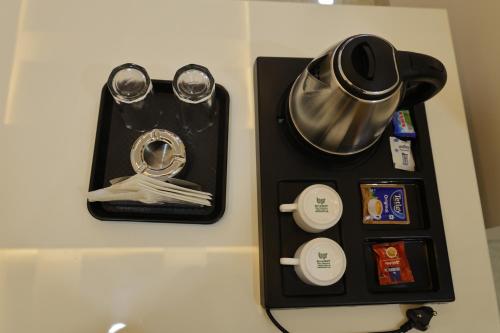 a black tray with cups and utensils on a table at Hotel The Prime Land in Hoshangābād