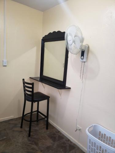 a chair and a mirror and a fan in a room at West Side Studio Apartments in Anasco