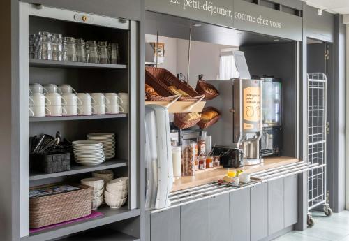 a kitchen with plates and dishes on shelves at B&B HOTEL Beauvais in Beauvais