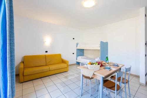a living room with a yellow couch and a table at Spluga "Relax & Apartaments" by Alfio Colombo in Sorico
