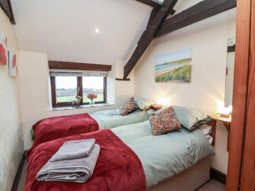 a bedroom with two beds with red sheets at Badgers Sett in Bude