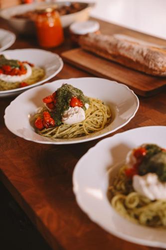 a table topped with plates of pasta and sauce at Les Chambres de Lasserre - Chambres et Table d'hôtes in Lasserre