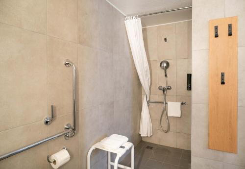 a bathroom with a shower with a stool in it at B&B HOTEL Vannes Est Golfe du Morbihan in Vannes