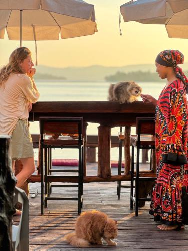 two women standing around a table with a dog and a cat at Bankruchaem Homestay Kohpu in Ban Klang
