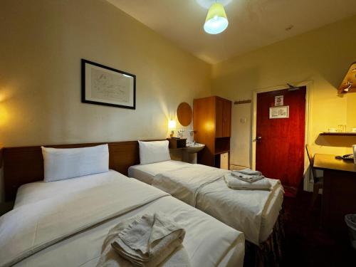 a hotel room with two beds and a red door at Bridge Park Hotel in London