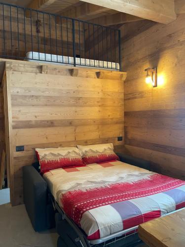 a bed in a room with wooden walls at Sabbionaccio Apartments & Spa in Chiesa in Valmalenco
