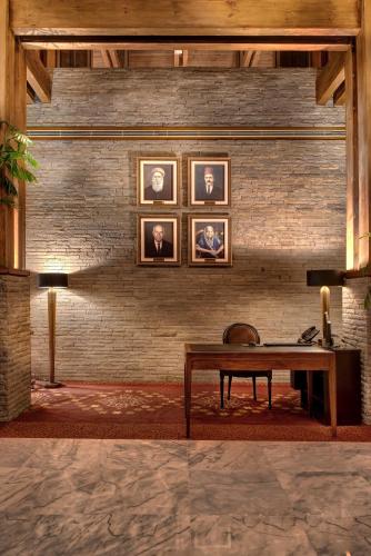 a room with a table and portraits on a brick wall at Pearl Continental Hotel, Muzaffarabad in Muzaffarabad