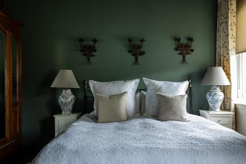 a bedroom with a bed with white sheets and two lamps at The Townhouse Sherborne in Sherborne
