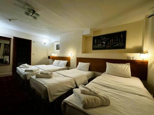 three beds in a hotel room with white sheets at Bridge Park Hotel in London