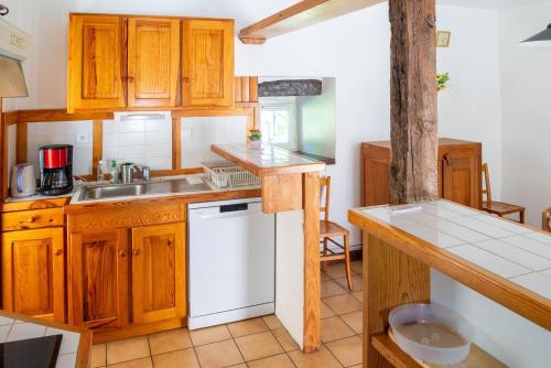 - une cuisine avec des placards en bois et un lave-vaisselle blanc dans l'établissement Gîte La Cazelle 4/6 personnes du Presbytère, à Saint-Georges-de-Lévéjac