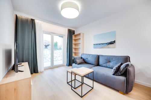 a living room with a blue couch and a tv at ReVital Mechelinki by Homeprime Parking Free in Mechelinki
