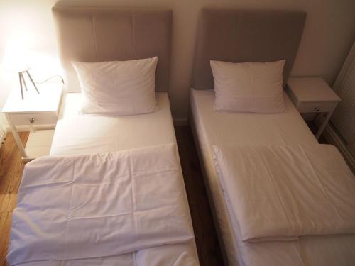 two beds in a small room with white sheets and pillows at Tawerna Panorama in Stepnica