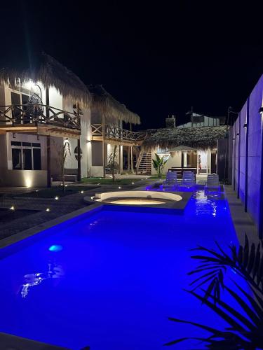 a blue swimming pool in front of a house at night at Dunamar Beach House in Los Órganos