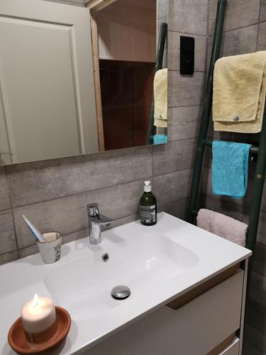La salle de bains est pourvue d'un lavabo avec une bougie. dans l'établissement Etape magique a l'Escale, à Guilherand