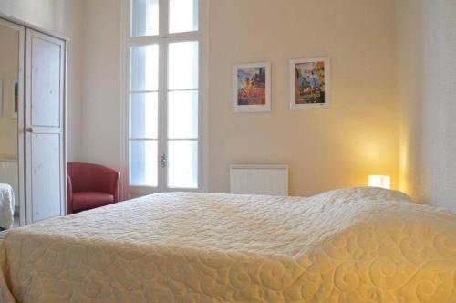 une chambre avec un grand lit et une chaise rouge dans l'établissement Appart 5 pièces 6 couchages BANYULS SUR MER BN290-002, à Banyuls-sur-Mer