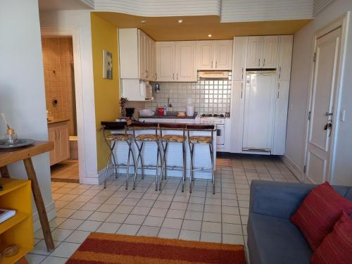 eine Küche mit weißen Schränken und Barhockern in der Unterkunft apartamento em aréa nobre in Vitória da Conquista