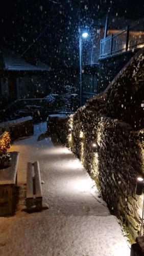 a snow covered sidewalk with a bench at night at la foret in Metsovo