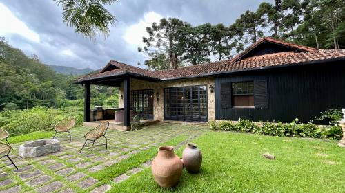 Una casa con dos jarrones en el césped. en Casa 04 Vale Boa Vista - Casa Charmosa com 3 Suítes e Acesso à Área de Lazer Completa de Condomínio, en Teresópolis