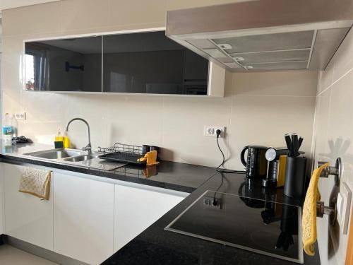 a kitchen with white cabinets and a black counter top at Ramona in Aveiro