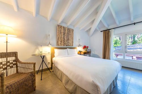a bedroom with a large bed and a chair at Hotel Huerto del Cura in Elche