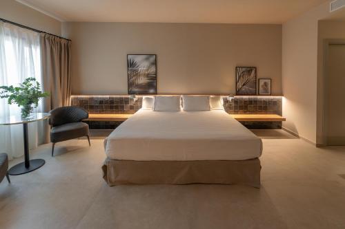 a bedroom with a large bed and a chair at Hotel Huerto del Cura in Elche
