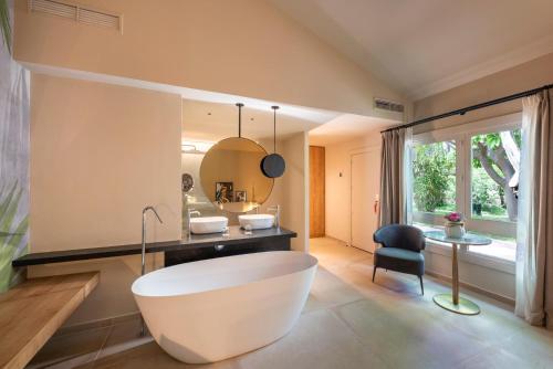 a bathroom with a large white tub and a chair at Hotel Huerto del Cura in Elche