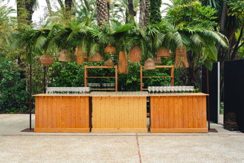a bar with benches and palm trees behind it at Hotel Huerto del Cura in Elche