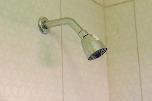 einen Duschkopf im Bad mit weißen Fliesen in der Unterkunft Pousada kanoas suites in São José da Coroa Grande