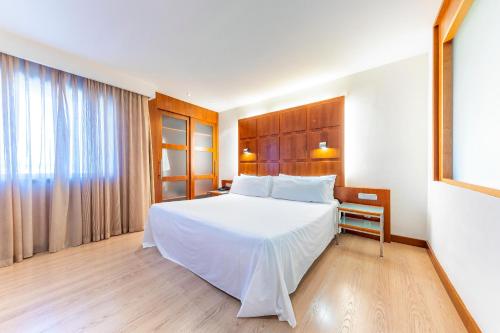 a bedroom with a large white bed and a window at Port Azafata Valencia in Manises