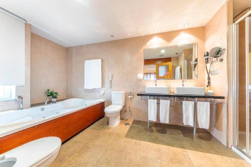 a bathroom with a tub and a toilet and a sink at Port Azafata Valencia in Manises