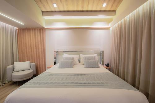 a bedroom with a large white bed and a chair at Mercure Curitiba Batel in Curitiba