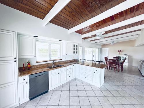 a large kitchen with white cabinets and a dining room at Flamingo House - Turks & Caicos in Turtle Cove