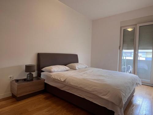 een slaapkamer met een groot bed met witte lakens en een raam bij Central Point • Apartment 59 in Podgorica