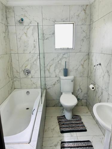 a bathroom with a toilet and a tub and a sink at kwamapulaneng guest house in Matrooster
