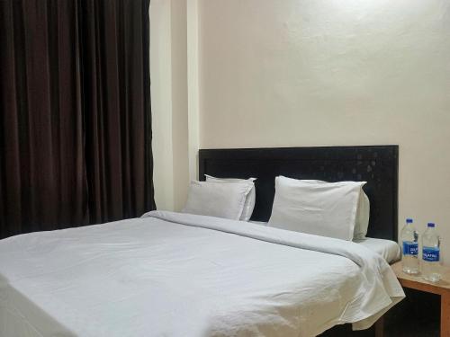 a bed with white sheets and pillows next to a window at Verma Guest House in Dharmsala