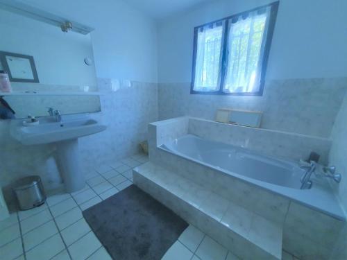 une salle de bain blanche avec une baignoire et un lavabo dans l'établissement Charmante maison proche plage - 5242, à Soulac-sur-Mer