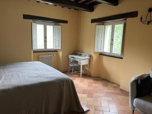a bedroom with a bed and a table and windows at La Melagrana in Brisighella
