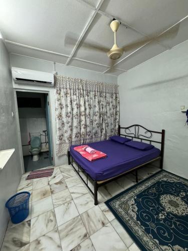 a bedroom with a purple bed and a bathroom at D' Gerik Homestay Taman Sinaran in Gerik