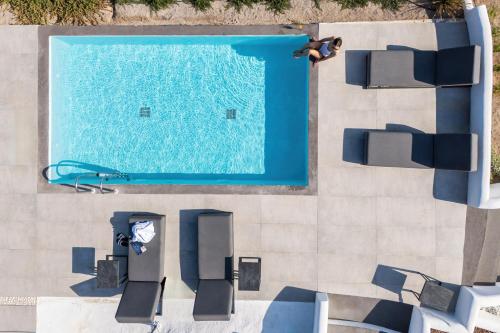 an overhead view of a swimming pool with chairs and a person at Blé Suites Santorini in Imerovigli