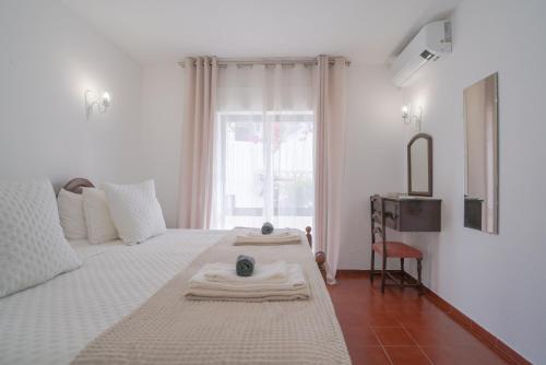 een witte slaapkamer met een bed met handdoeken erop bij 5 bedroom Beach house in Luz, Lagos in Luz