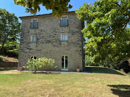 an old stone house with two windows and a yard at La Melagrana in Brisighella