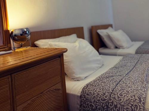 マンドリアにあるMermaid Holiday Apartmentsのベッド2台とワイングラスが置かれたテーブルのある寝室