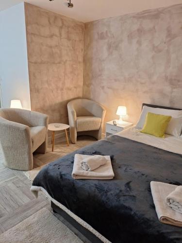 a bedroom with a large bed and a chair at Apartman Helena 2 in Lazarevac