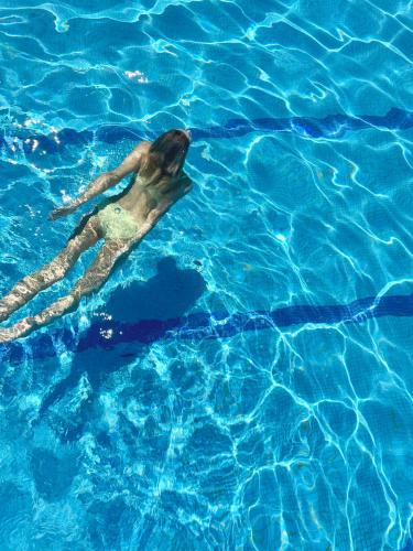a woman swimming in a pool of blue water at Villa Maier B&B & Apartments in Soprabolzano
