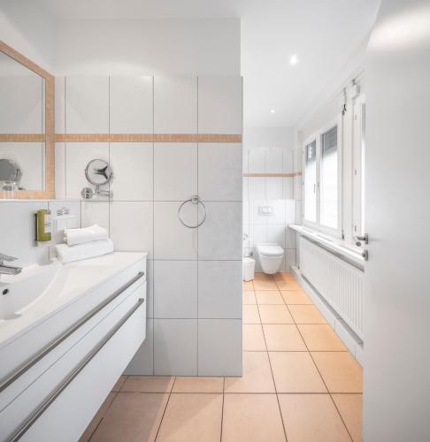 a white bathroom with a sink and a toilet at BoardingWorld Heidelberg in Heidelberg