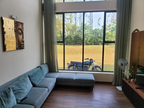 a living room with a blue couch in front of a window at Aurora-The Pool Villa in Kozhikode