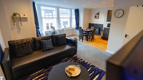 a living room with a leather couch and a table at Cardiff City Centre - Luxury Apartments in Cardiff