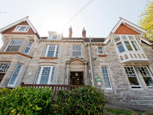 an old stone house with a large building at YHA Swanage in Swanage