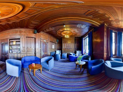 a room with blue chairs and tables and a ceiling at YHA Swanage in Swanage