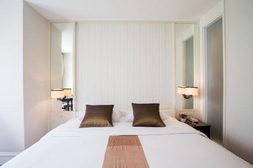 1 dormitorio con 1 cama blanca grande con almohadas marrones en Aphrodite Inn Bangkok, en Bangkok